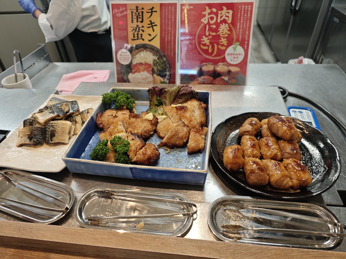 ドーミーイン宮崎の朝食会場の料理台。「チキン南蛮」「肉巻きおにぎり」のメニュー札と料理
